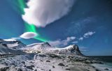 Green aurora above a snowy mountain landscape