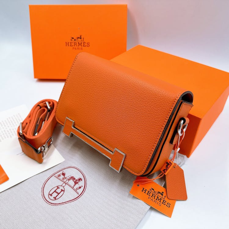 Orange Hermès leather handbag photographed with its signature orange box and ribbon