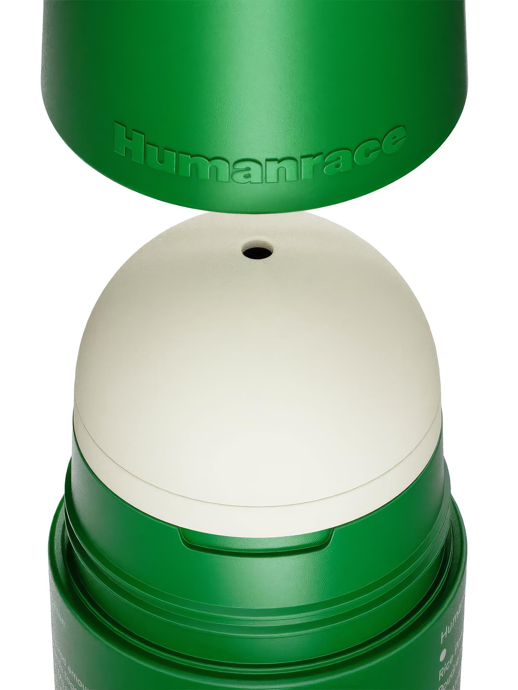 Humanrace skincare jar opened to reveal a refillable cream-colored inner pod inside a green outer shell with embossed Humanrace wordmark